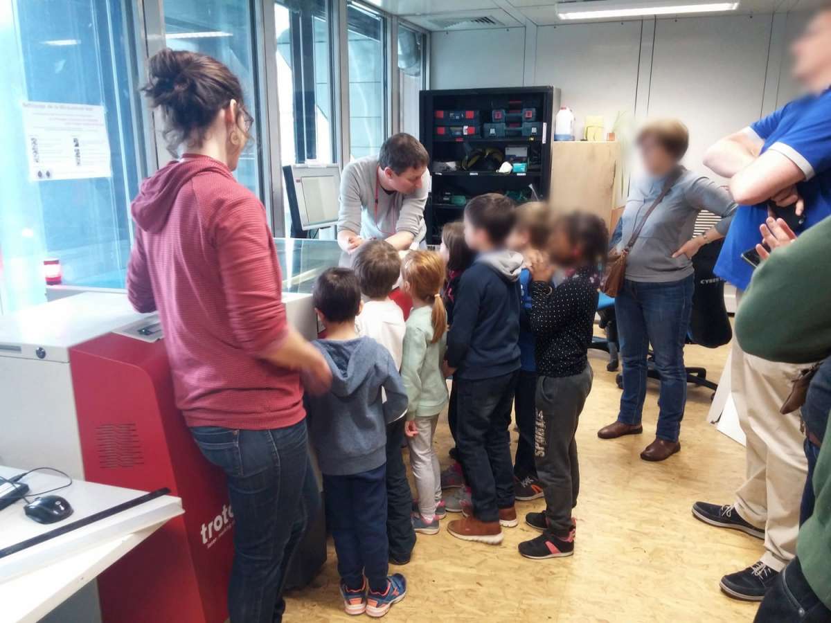 At the Fab Lab, Thierry Dass&eacute; and H&eacute;l&egrave;ne Malcuit present the laser cutter. The machine cuts out the letters drawn by the children in the previous workshop.